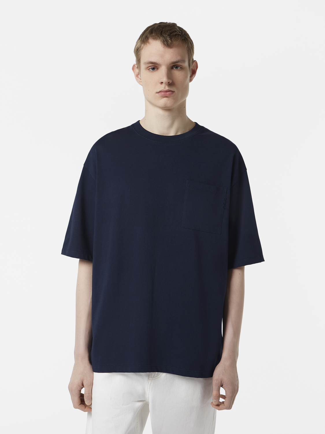 Person wearing a navy blue t-shirt and white pants on a light gray background