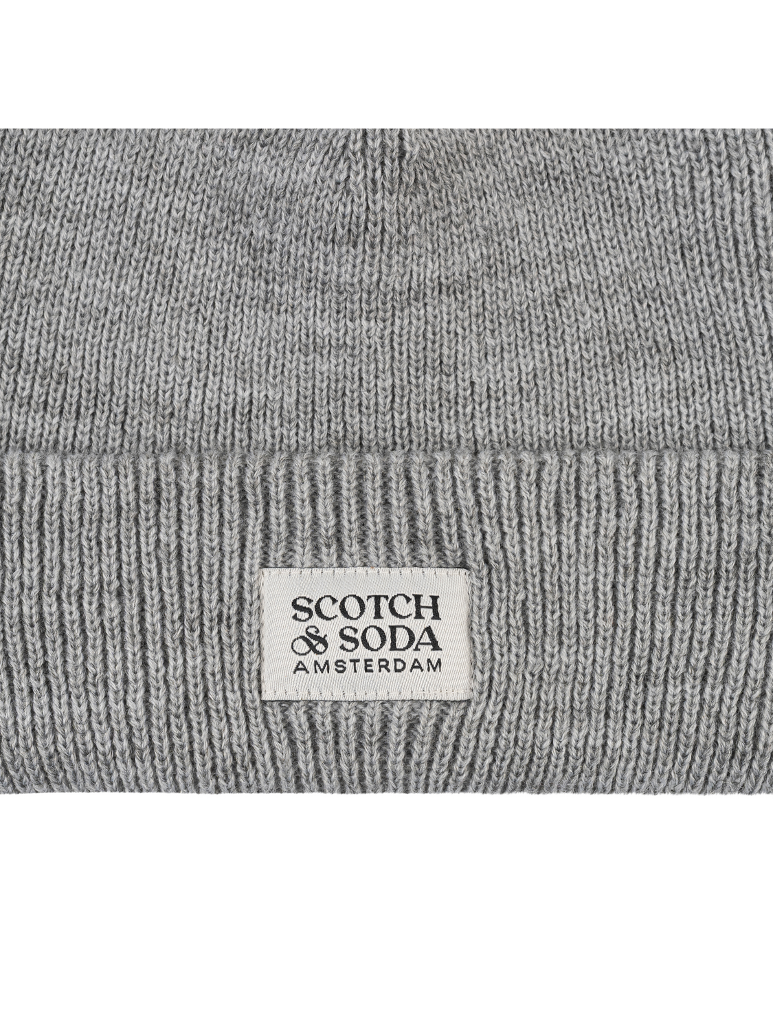 Close-up of a gray ribbed knit beanie with a white rectangular label reading SCOTCH & SODA AMSTERDAM.