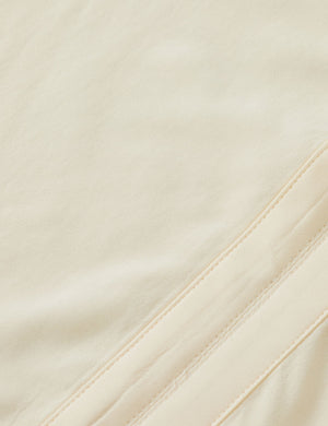 Close-up of beige fabric with a subtle texture and stitching detail.