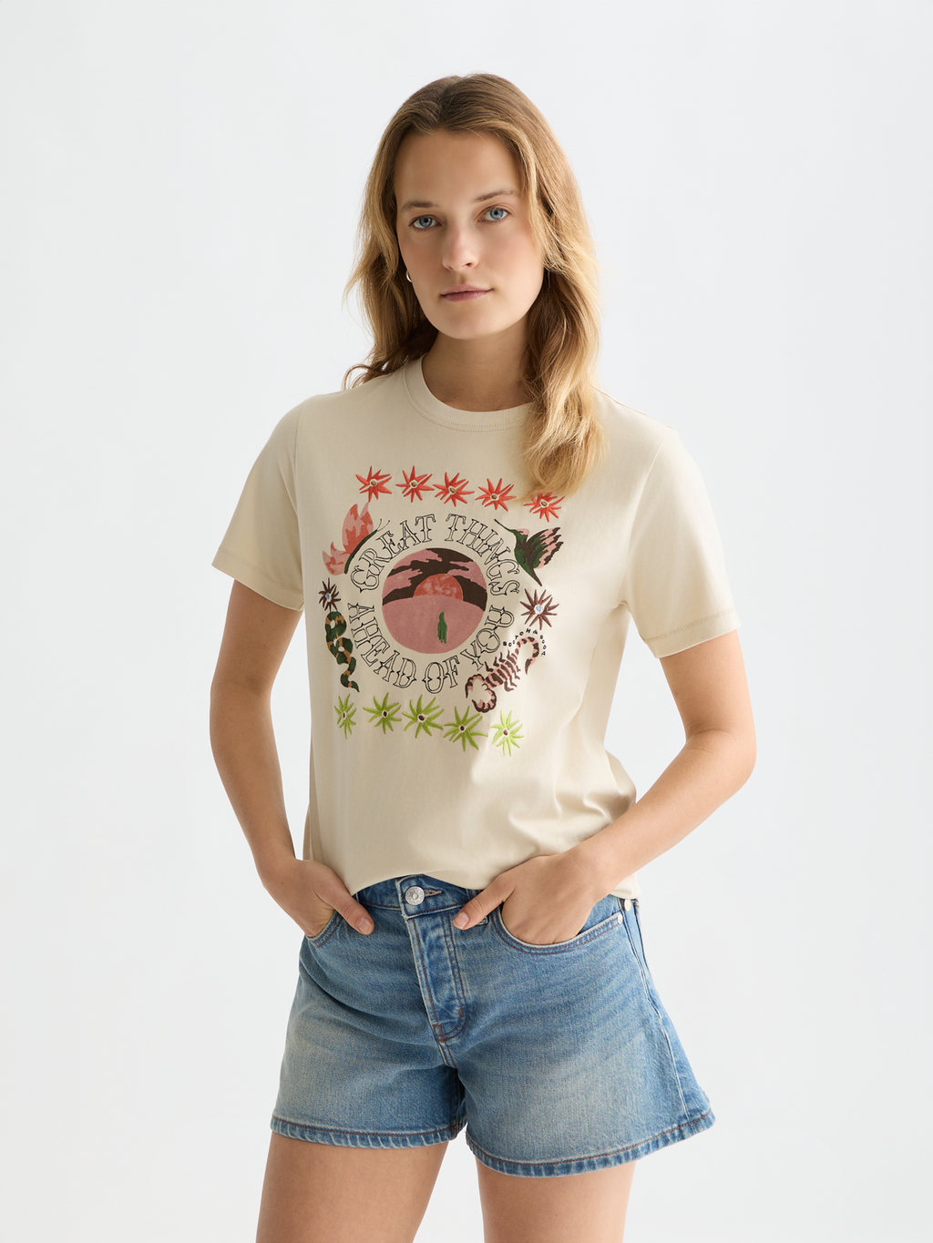Woman wearing a graphic t-shirt and denim shorts on a plain background
